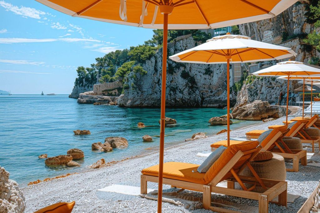 Vue panoramique d'une plage de galets avec des parasols oranges et des transats.
