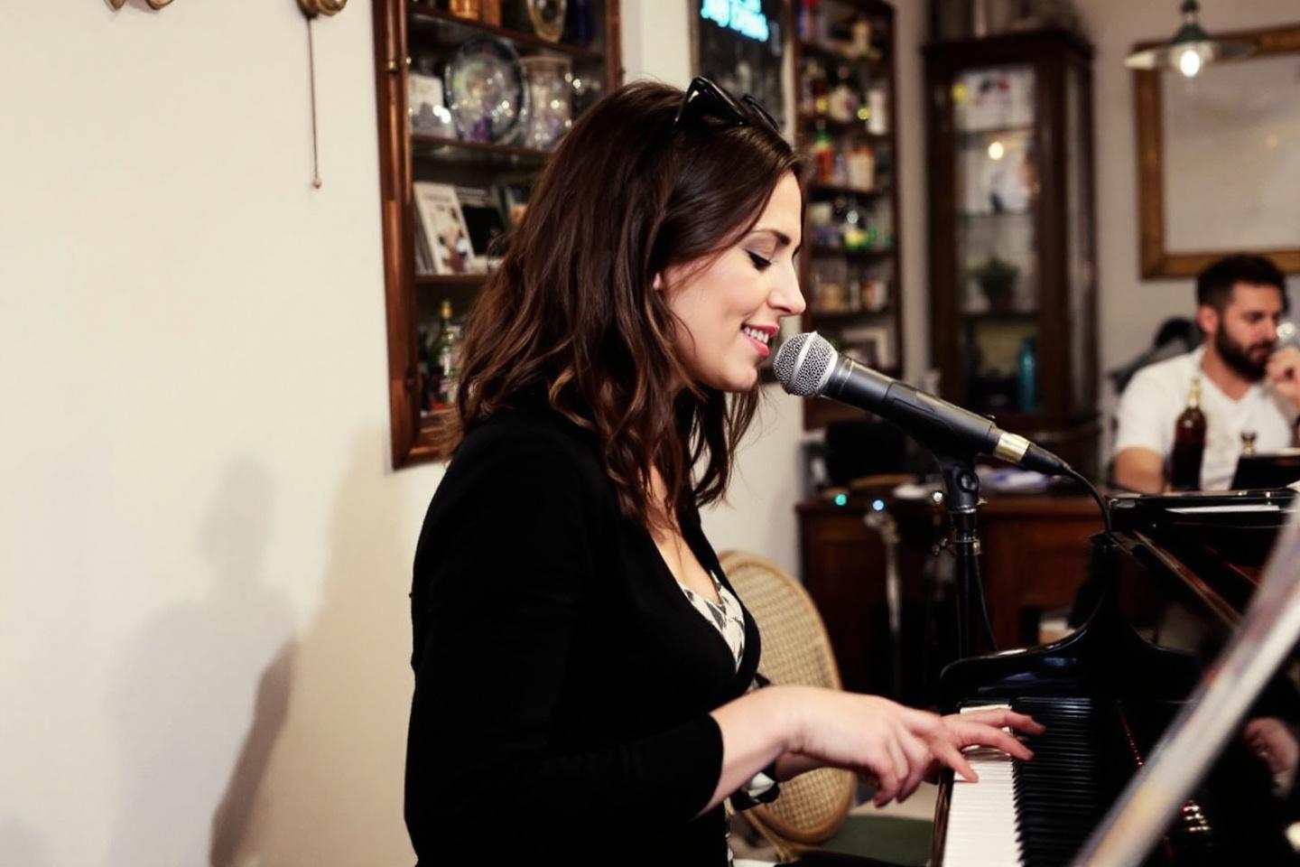 Femme brune chantant au microphone en jouant du piano