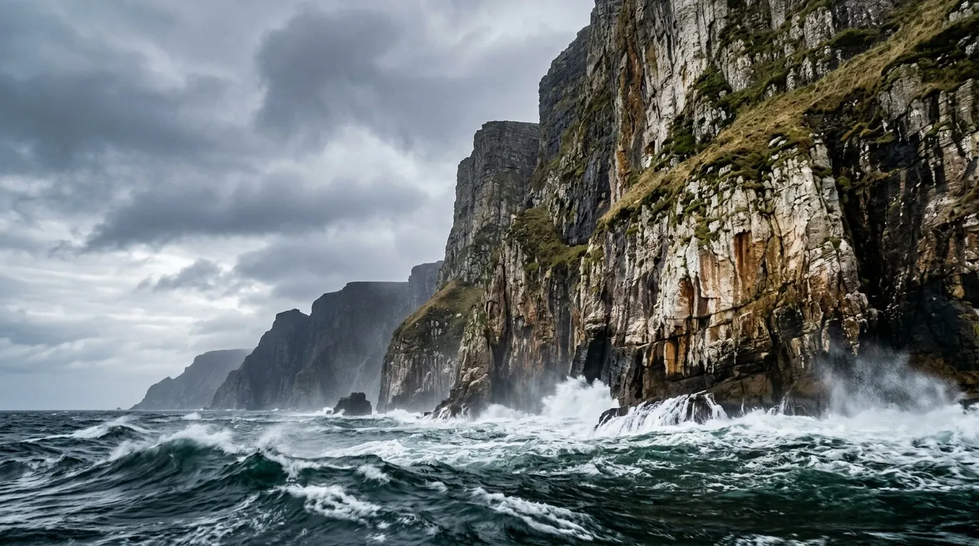 Hautes falaises rocheuses avec vagues déferlantes sous ciel nuageux